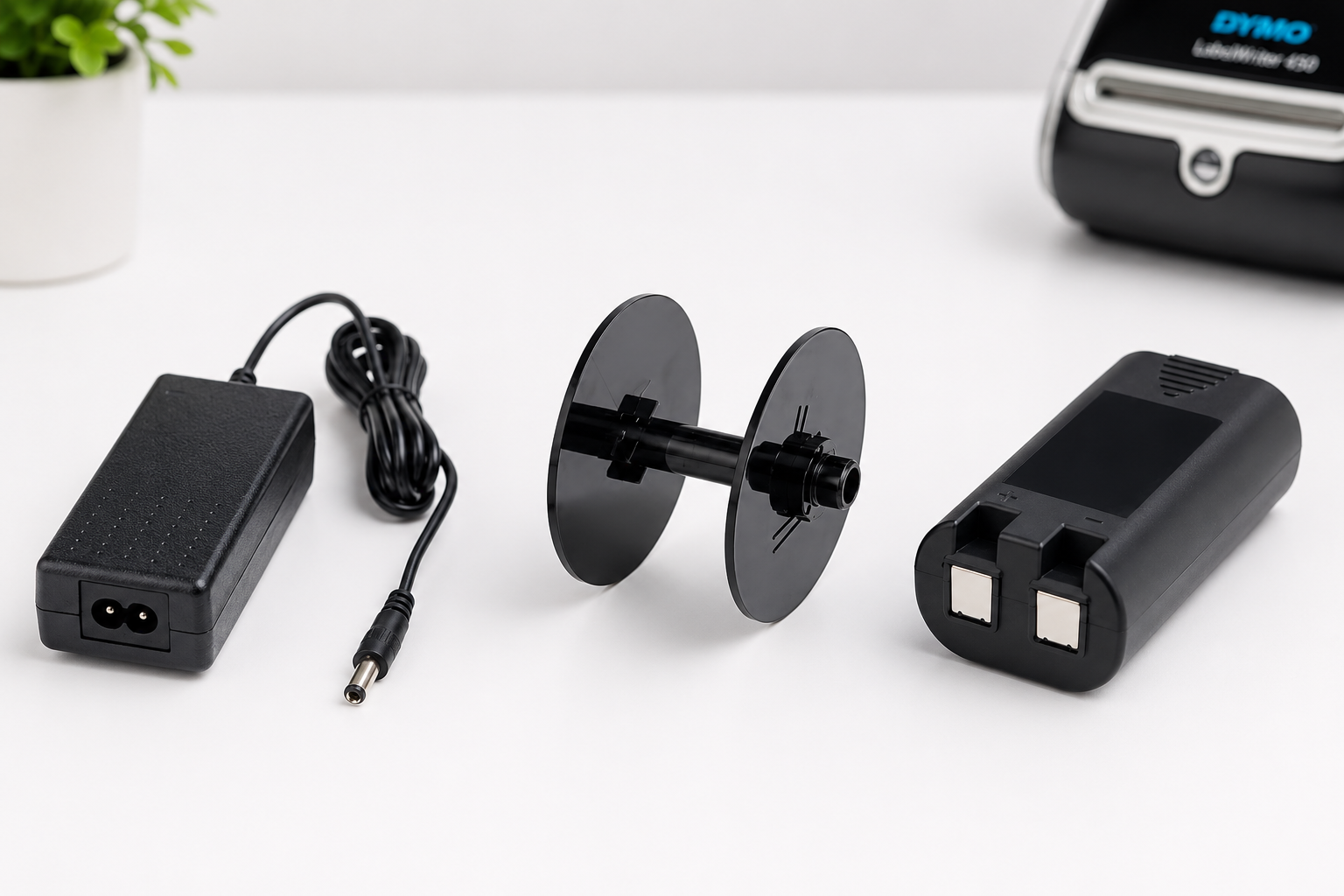 DYMO power adaptor, label spool and rechargeable battery arranged on a clean white office desk.