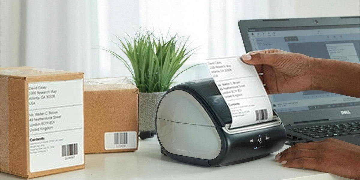 DYMO LabelWriter 5XL printing a wide shipping label beside parcels and a laptop