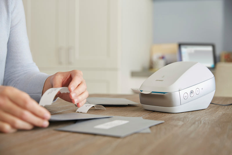 Person preparing a parcel with DYMO LabelWriter large shipping label on box