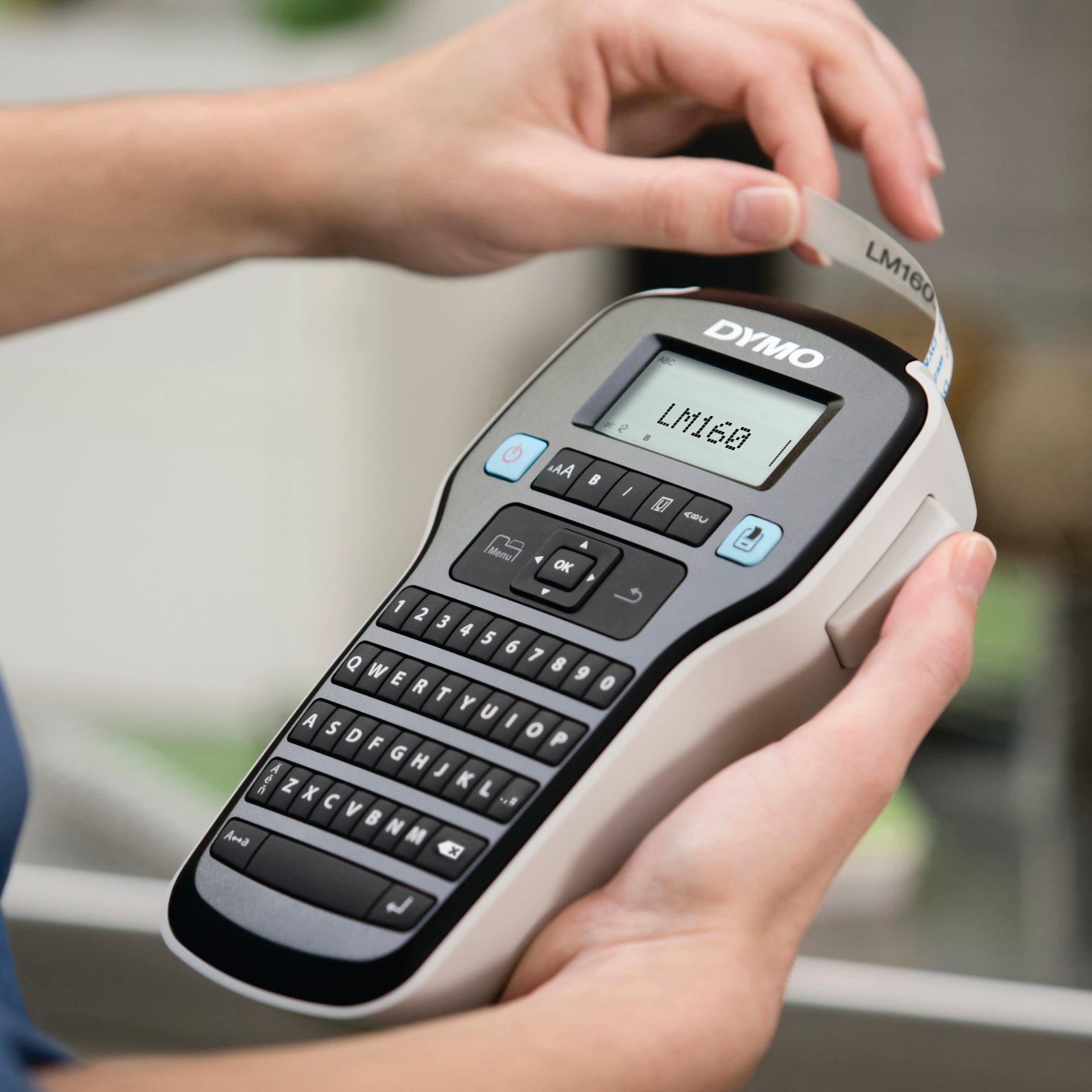 Hands loading label tape into a Dymo LabelManager handheld label maker