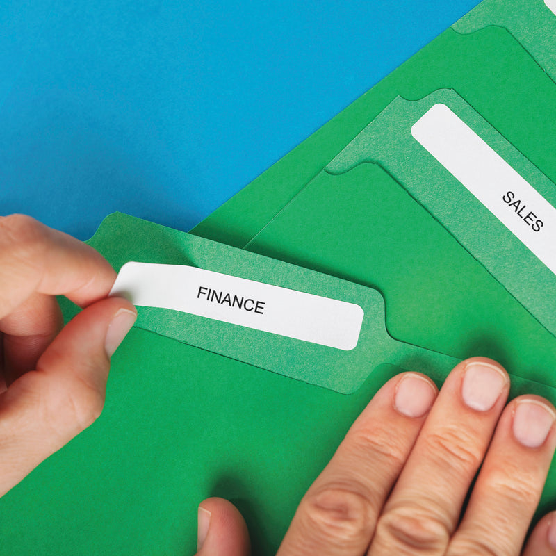 Hand placing a white label onto a green folder