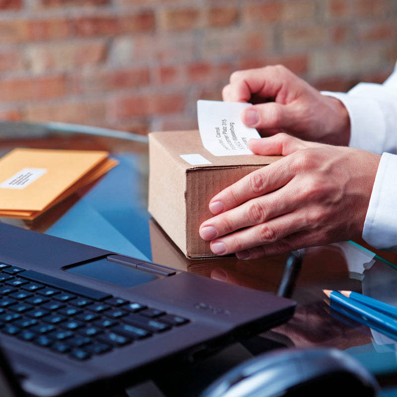Hands applying a shipping label to a cardboard box