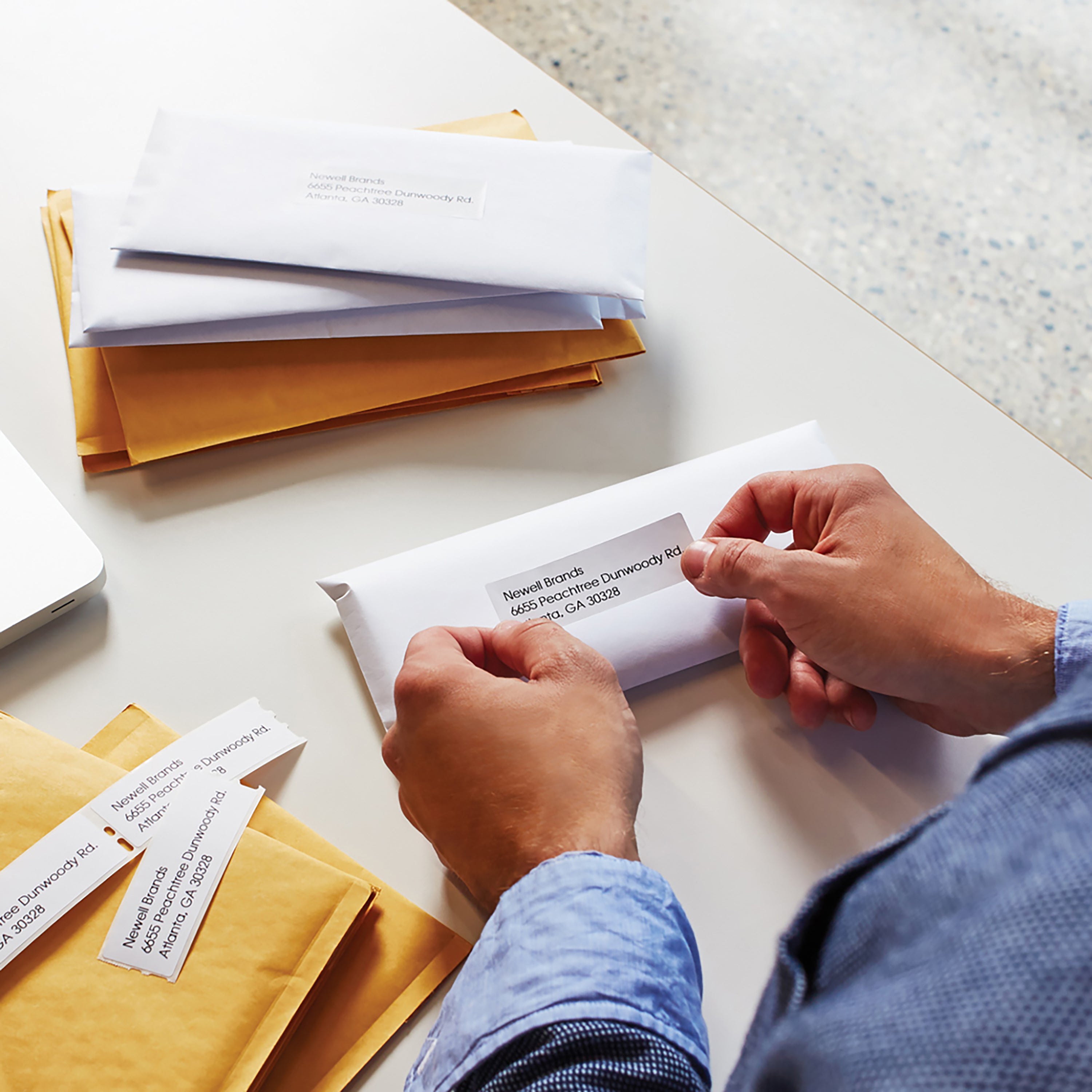 Person writing and organising paperwork with address labels on a desk