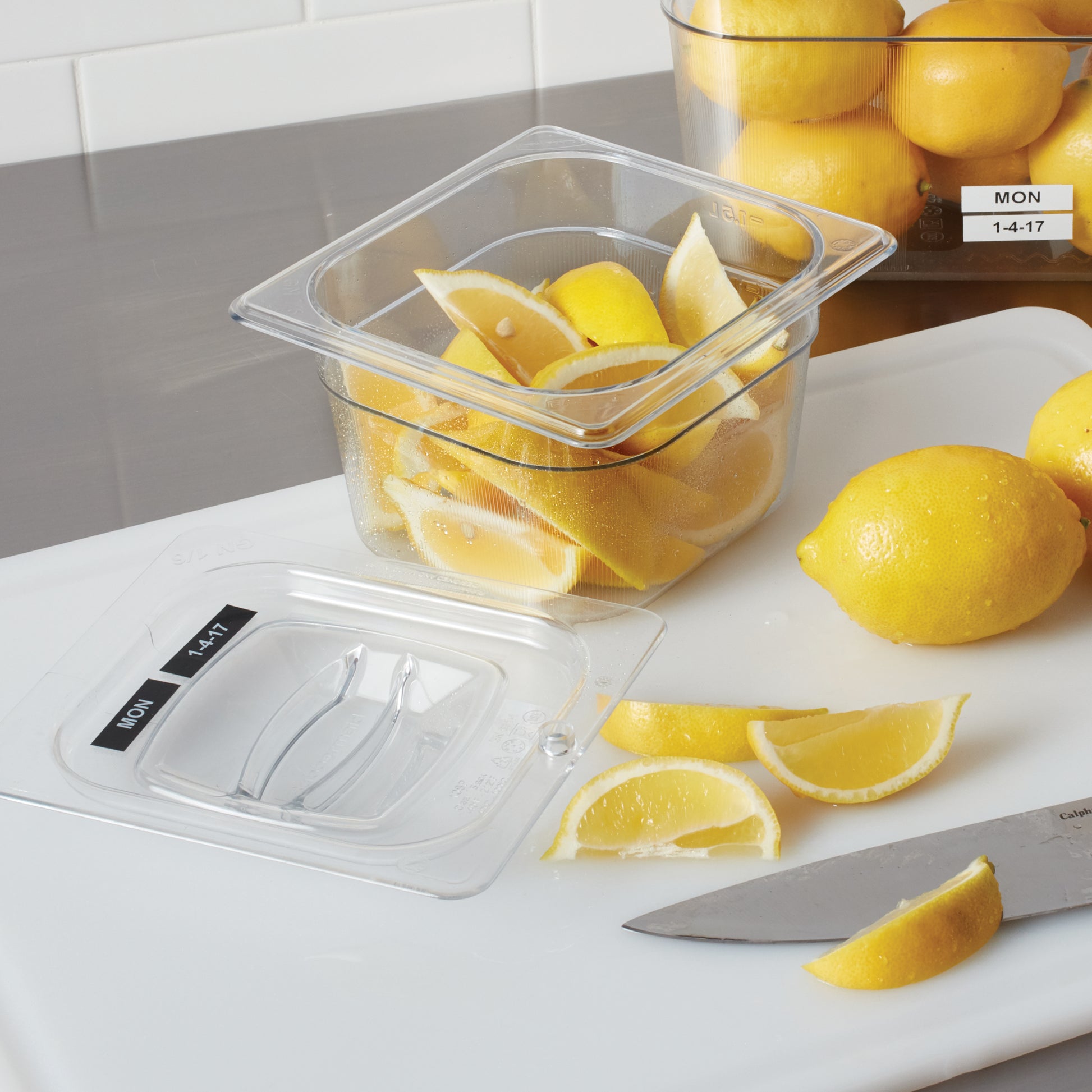 Labelled kitchen jars and food storage containers beside fresh lemons