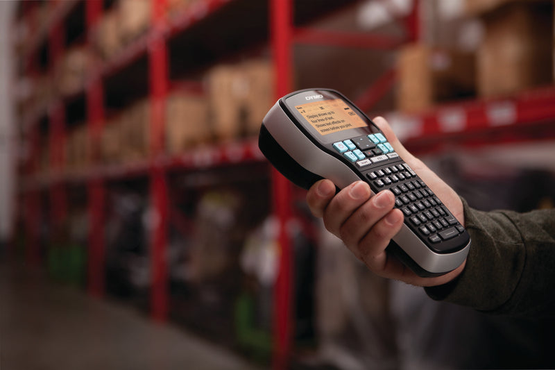 Person holding a DYMO LabelManager 420P in a warehouse aisle for portable shelf and stock labelling