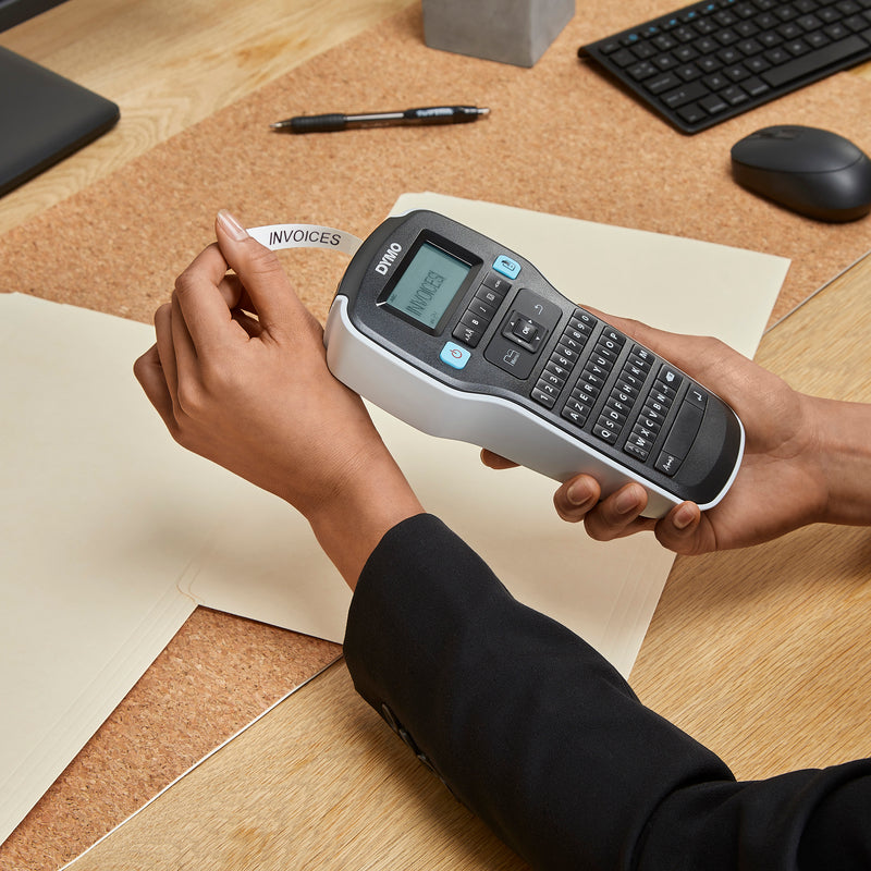 Person holding a Dymo LabelManager label maker at a desk