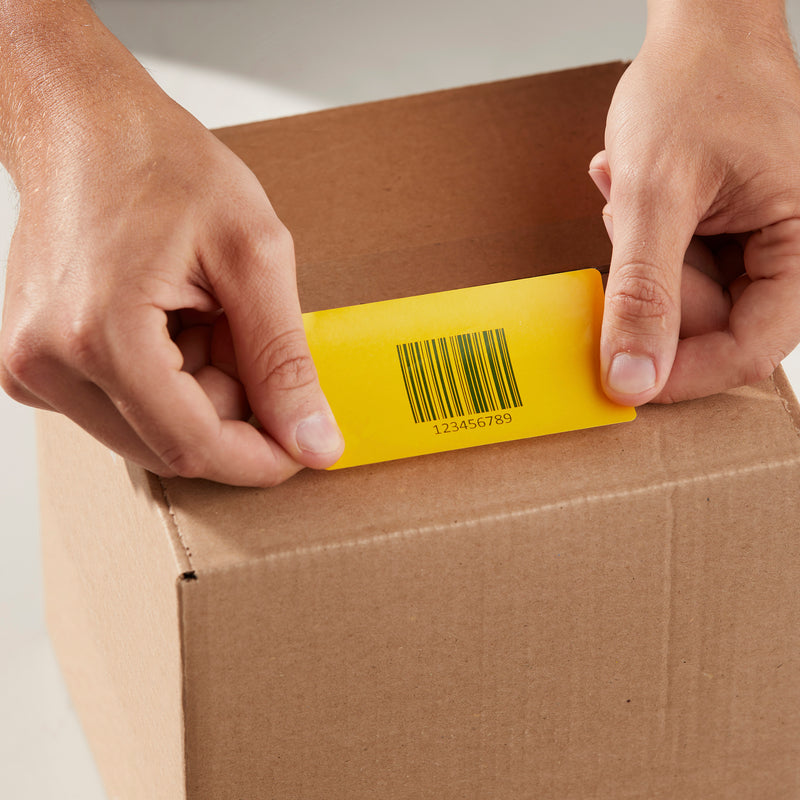 Hands applying a yellow warning label to a cardboard box