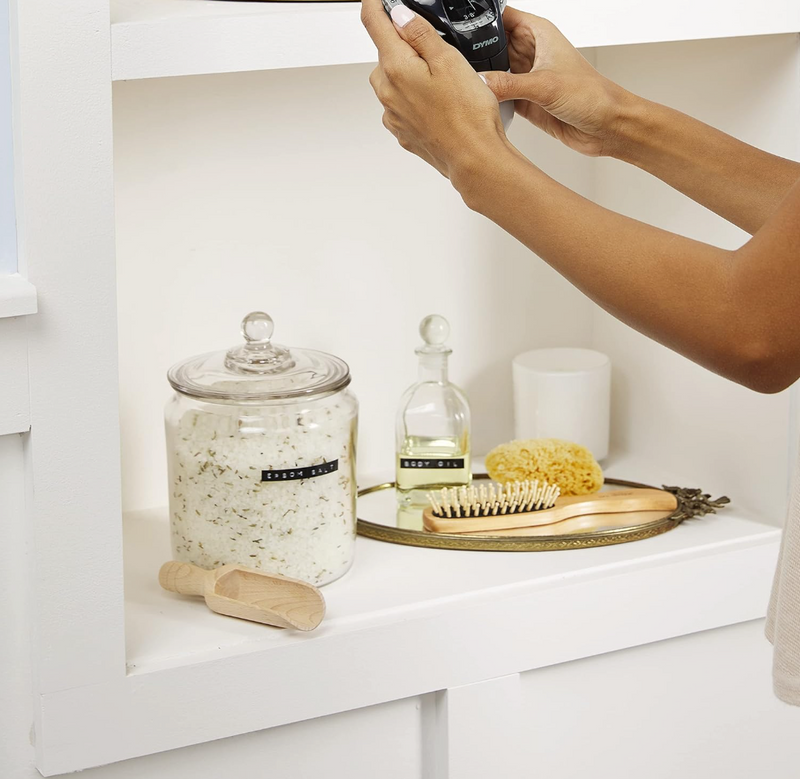 Hand applying DYMO embossing label tape to a kitchen storage jar