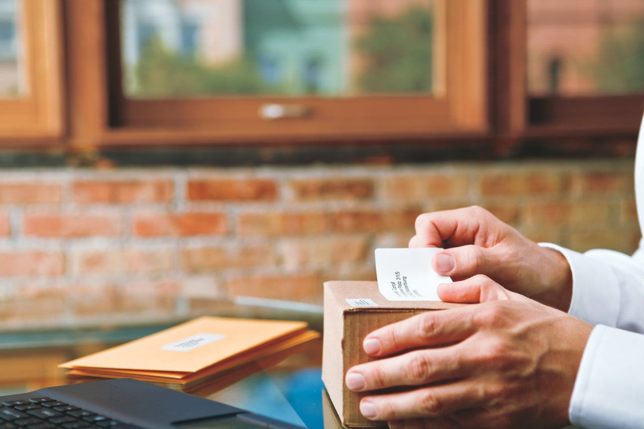 Hand applying a shipping label to a cardboard box