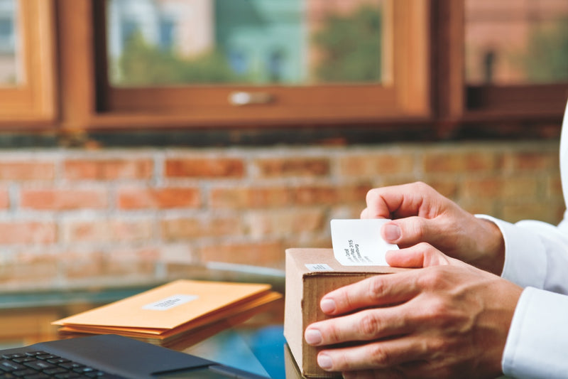 Hand applying a shipping label to a cardboard box