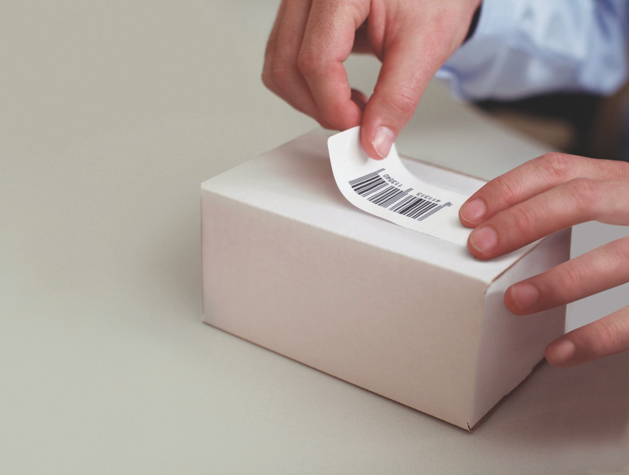 Hands applying a label to a small white parcel