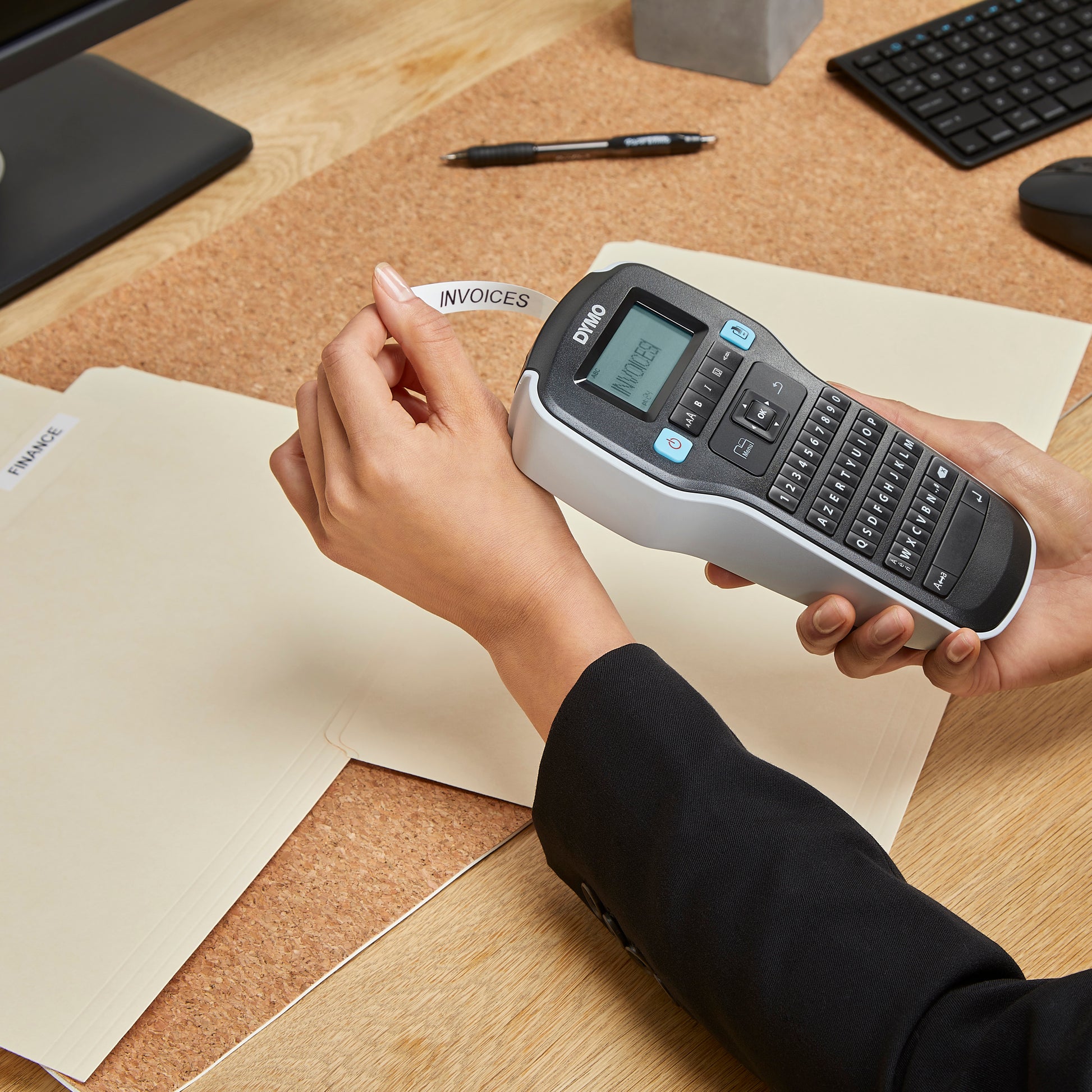 Person using a DYMO handheld label maker to print an invoices label for office file folder organisation